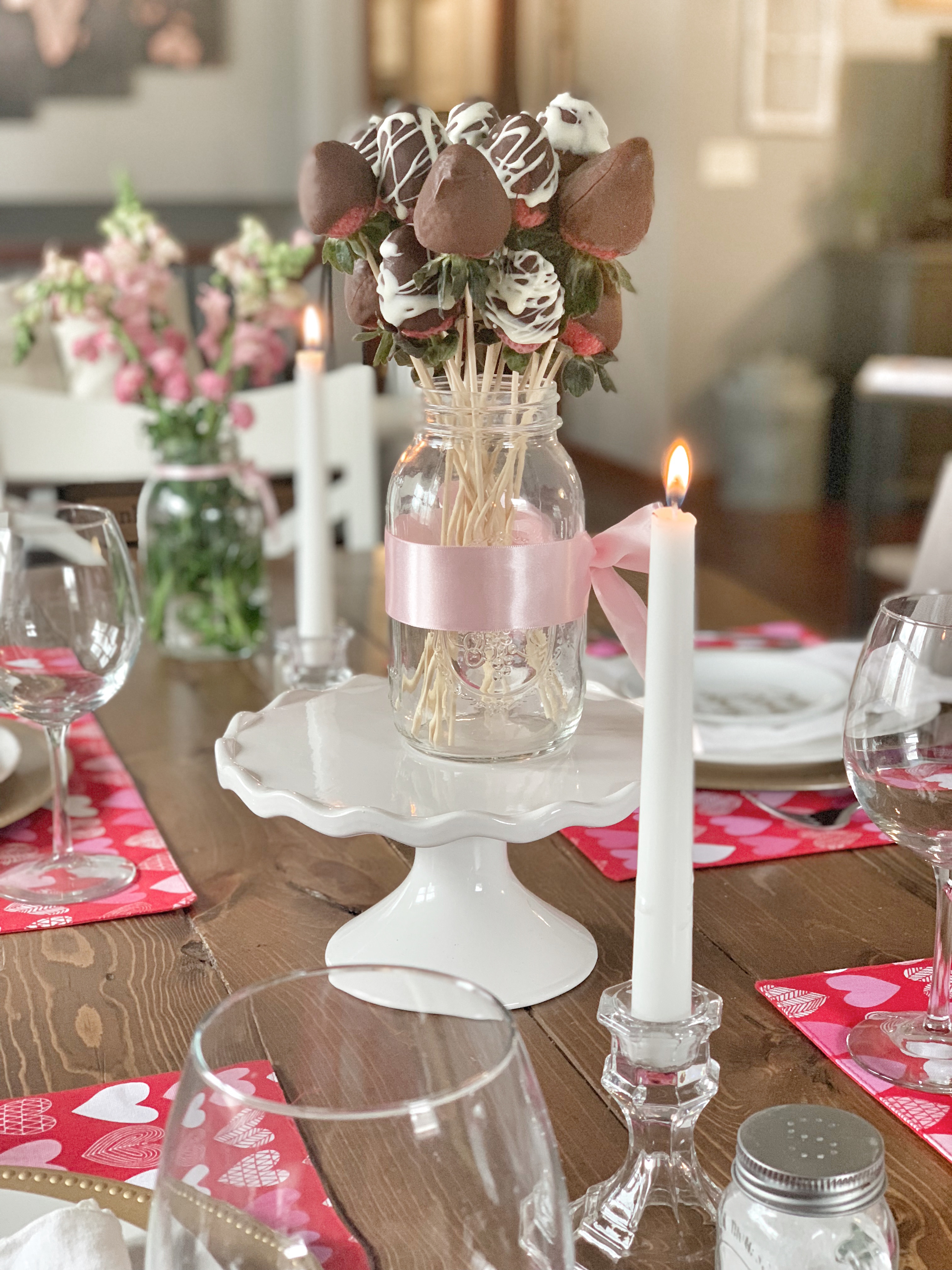 chocolate covered strawberries, cake stand, candles, pink ribbon, center piece